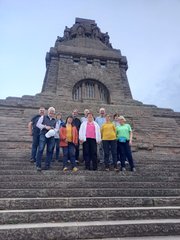 Gruppenbild mit Damen, Herren und einem Denkmal